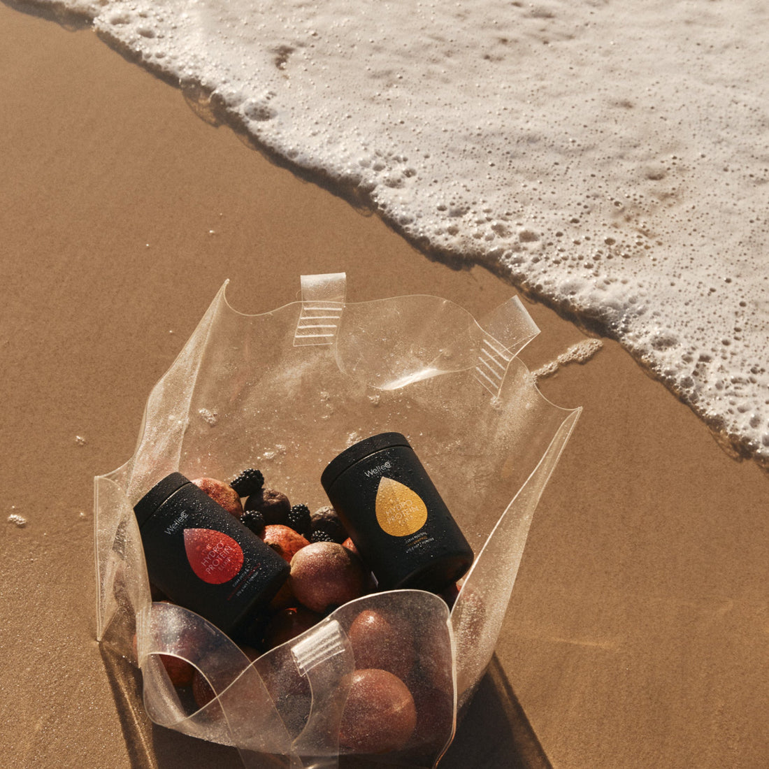Jars and fruits on a beach near the shoreline.
