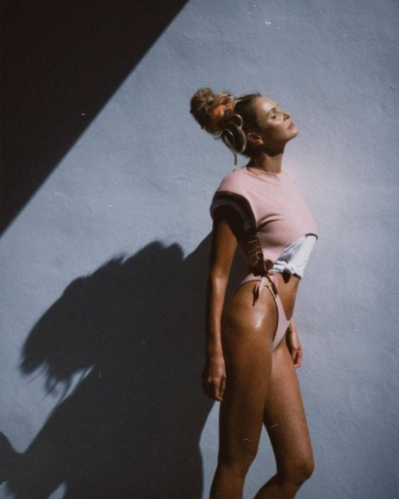 A person standing against a wall, casting a shadow in soft light.